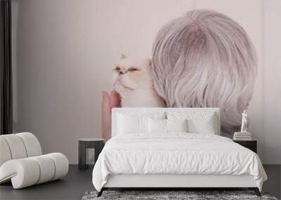 A gray-haired older woman in a gray turtleneck has a cute beige cat on her shoulder. The view from the back. Wall mural