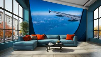 View of the wing of an airplane flying over the mountains and the sea Wall mural