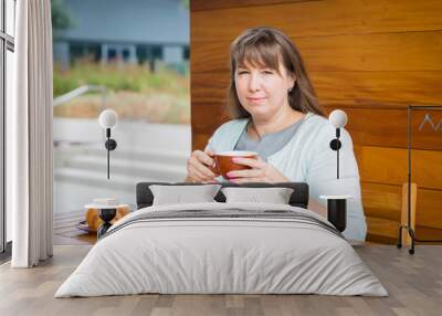 Young Caucasian woman with straight hair drinking tea in a coffee shop Wall mural