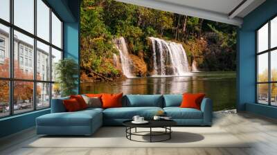 view of long-tail boat and raft house with many tourist playing in Kwai Noi River and Say Yok Yai Waterfall with green forest background, Kanchanaburi, west Thailand Wall mural