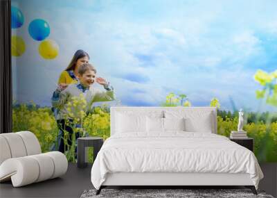 Little happy girl with blue and yellow .Yellow field of rapeseed. happy running kids. concept of freedom, summer. Rapeseed is an alternative energy. Wall mural