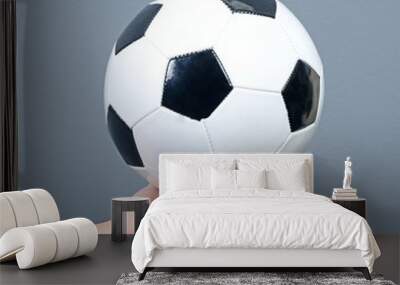 Hand holding football against gray background Wall mural