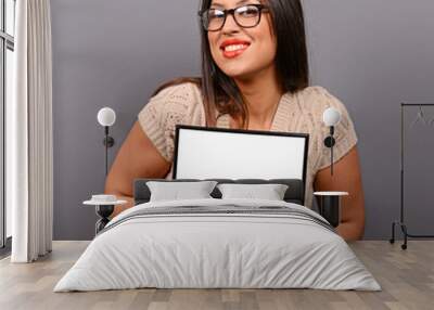 Portrait of smiling woman holding blank photo frame against gray Wall mural