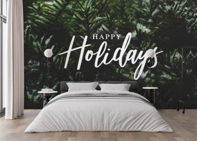 Happy Holidays Text Over Winter Evergreen Branches Covered in Snow Wall mural