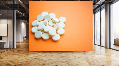 A pile of yellow ascorbic acid pills on an orange background. Synthetic Vitamin C. Prevention or treatment of the common cold. Dietary supplement Wall mural