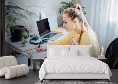 Flexible working, flexible work. Young woman freelancer working at home office with laptop and documents. Flexible work schedule. Wall mural