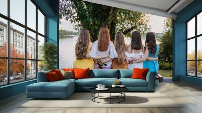 Group of happy young women, female friends having fun on summer nature background. Many young female friends together looking the sunset. Female Friendship and Forever friends concept Wall mural