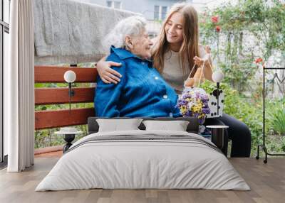 Volunteer girl and Senior elderly woman with gift, flowers bouquet and basket of groceries Wall mural