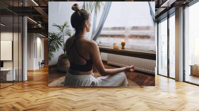 Young woman sitting on the floor, lights candles, enjoy meditation, do yoga exercise at home. Mental health, self care, No stress, healthy habit, mindfulness lifestyle, anxiety relief concept Wall mural