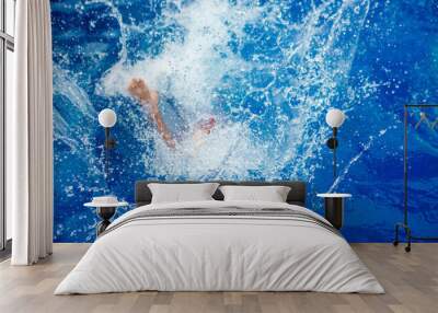 person jumping into the blue water. Are visible only to feet. Bright splashes of active spread in all directions. The mood of a summer vacation in a resort tropical. Catch joyful moment Wall mural