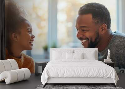 A man and a girl are sitting at a table in a kitchen, smiling and laughing. They are enjoying each other's company and having a good time Wall mural