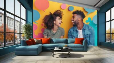 A man and woman are sitting on a yellow background with a lot of speech bubbles. They are smiling and laughing, and the speech bubbles are in different colors. Scene is happy and lighthearted Wall mural