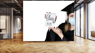 A student in mask is wearing a graduation cape and robe holding blank copy space place concept of the class of 2021 coronavirus pandemic of the covid. Graduation student on white background Wall mural