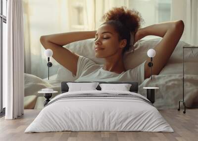 A woman is laying on a bed with her head on her hand. She is smiling and she is relaxed Wall mural