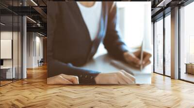 Accountant checking financial statement or counting by calculator income for tax form, hands close-up. Business woman sitting and working with colleague at the desk in office. Audit concept Wall mural