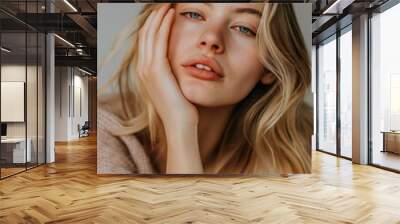 An attractive blonde woman with a pretty, wavy hairstyle posing for a close-up portrait, showcasing natural beauty and healthy skin with a focus on skincare and makeup. Wall mural