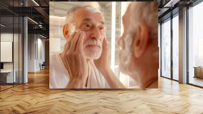 An elderly man applies cream to his face. Reflection in the mirror Wall mural