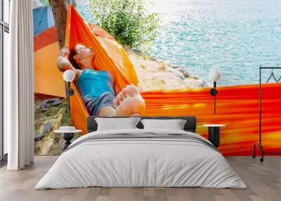 Barefoot woman sleeping in hammock on coast in camping. Wall mural