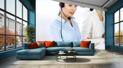 Blond woman call operator is using computer and headset for consulting clients online. Group of diverse people working as customer service occupation. Business concept Wall mural