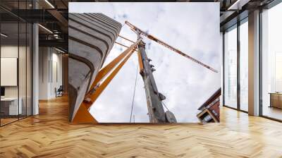 Bottom view of Tower crane against cloudy sky Wall mural