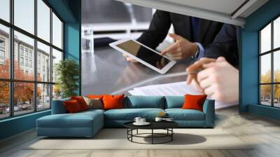 Businessman using tablet computer and work together with his colleague or partner at the glass desk in modern office, close-up. Unknown business people at meeting. Teamwork and partnership concept Wall mural