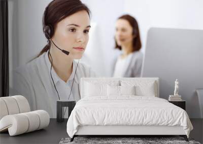 Call center. Casual dressed woman sitting in headset at customer service office. Group of operators at work. Business concept Wall mural