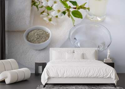 Ceramic bowl with green clay powder on white background. Ingredients for homemade facial and body mask or scrub and fresh sprig of flowering cherry. Spa and bodycare concept. Wall mural