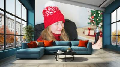 Christmas online congratulations.   Smiling woman making video call over smart phone on Christmas Eve to friends, parents and family, greeting with holidays. Christmas celebration on distance concept. Wall mural