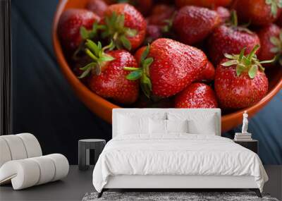 Close-up fresh ripe delicious strawberries in a orange bowl plate on wooden black table background. Antioxidant nutrition, healthy organic food concept. Copyspace. Flat lay. Daylight Wall mural