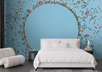 Colorful pastry sprinkle in the form of a round frame on a blue background. Wall mural