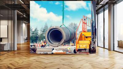 Concrete drainage pipe lifted by excavator during deep drainage works on construction site Wall mural