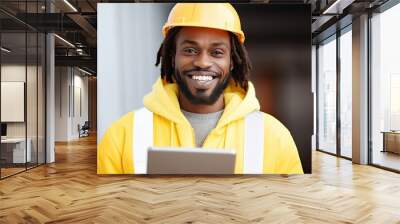 Confident black engineer working outdoors, wearing a hard hat, and using a tablet for construction. Wall mural