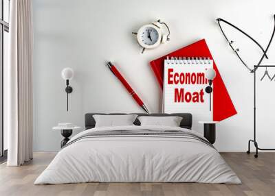 ECONOMIC MOAT text on notebook , red pen and notebook, business concept, white background Wall mural