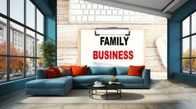 FAMILY BUSINESS text on a clipboard with keyboard on wooden background Wall mural