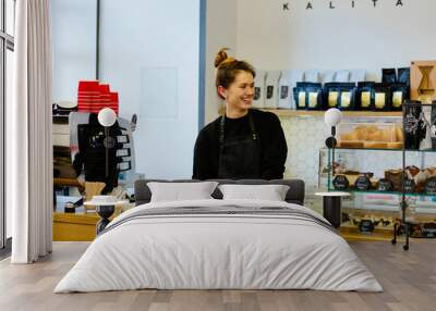 Friendly hospitable woman barista holding a two coffee cups with smiling face at cafe counter background, food and drink industry concept. Modern coffee shop interior. Wall mural