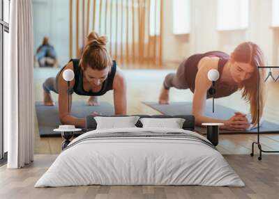 Front view of two sporty fit and slim middle aged women doing planking exercise indoors together with a natural light in modern interior sport studio hall or yoga class. Wall mural