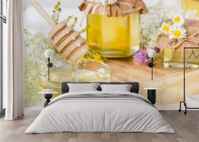 Full fresh liquid honey pots and honey stick with summer wild flowers on white table Wall mural