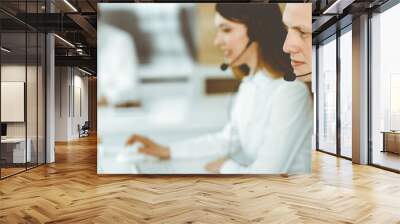 Group of diverse operators at work in call center. Businessman sitting n headset at customer service office. Business concept Wall mural