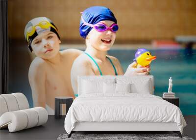 Happy children sitting on edge of the swim pool. Sport, recreation and childhood concept. Wall mural