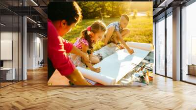 Happy mother, and two kids are painting in the park. The concept of a happy family. Wall mural