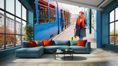 Happy tourist woman with small yellow luggage at the train station exited about oncoming journey. Enjoying travel by train concept Wall mural