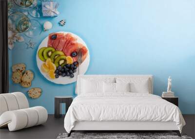 Christmas composition with meat, fruit, champagne and decorations on blue. Holidays food background with copy space for text. Top view. Flat lay. Wall mural