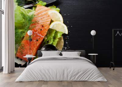 Delicious salmon fillet, rich in omega 3 oil, aromatic spices and lemon on fresh lettuce leaves on black background. Healthy food, diet and cooking background with copy space. Wall mural