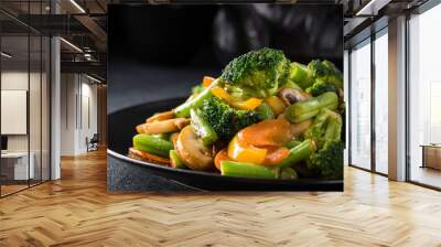 Hot stir fried vegetables on black plate. Healthy asian food concept with copy space. Wall mural