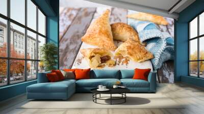 Puff pastry triangles filled with apples, dutch appelflappen on old cutting board. Homemade food concept with copy space. Wall mural