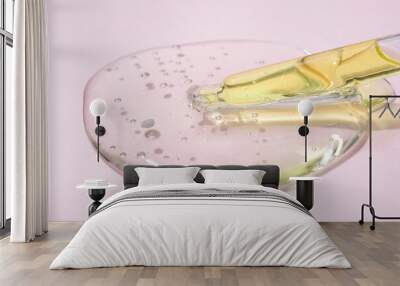 Fron view on pipette with serum or liquid yellow gel on light pink glass background. Beauty cosmetic concept Wall mural