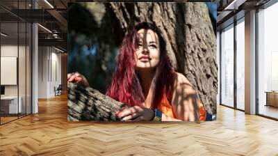 Portrait of a girl on a tree in a city park in summer Wall mural