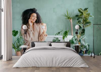 portrait of beautiful woman smiling while taking some facial cream isolated on white background with copy space Wall mural