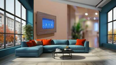 Smart home control panel on a beige wall in a modern hallway with warm lighting and blurred background Wall mural