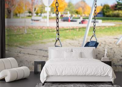 Swing on playground in park in autumn without people Wall mural